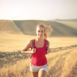 A woman jogging through vast, golden wheat fields under the summer sun, symbolizing freedom and adventure.